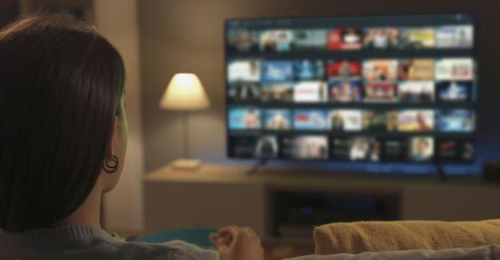 a woman eating popcorn and browsing a streaming app on her Samsung TV