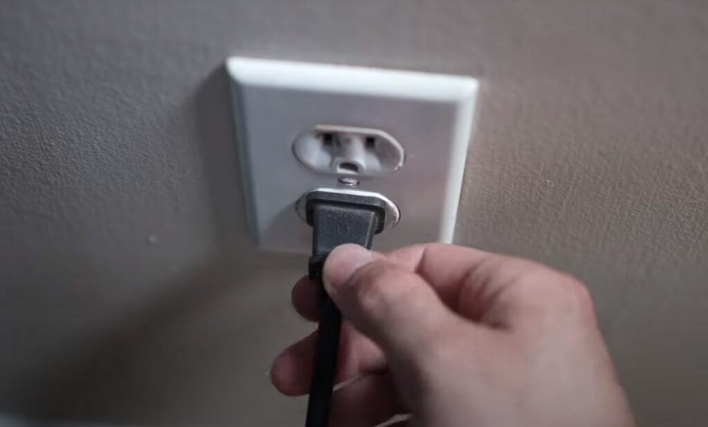 a hand holding a plug that is plugged in a socket