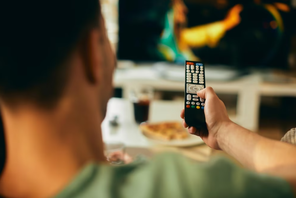 man holding a remote control watching TV