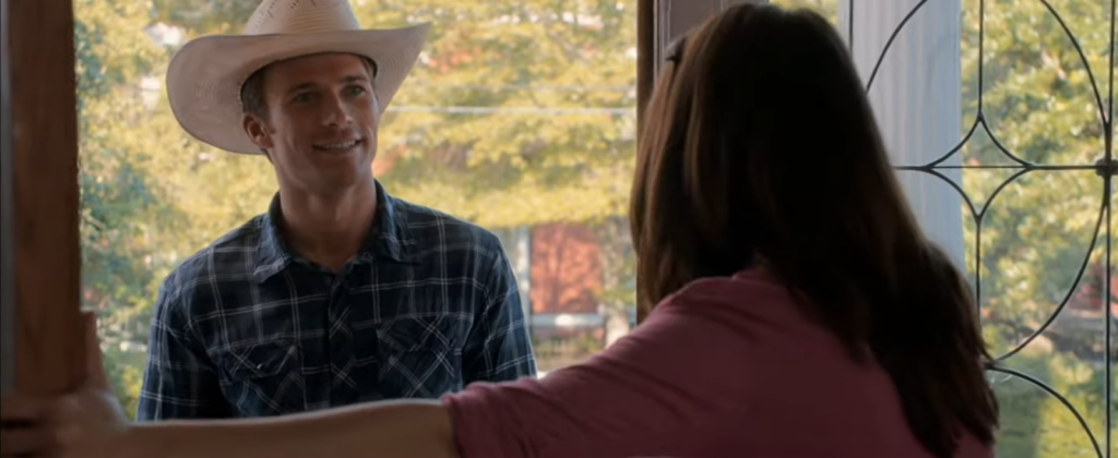 Man in a cowboy hat smiling to a woman near the doors