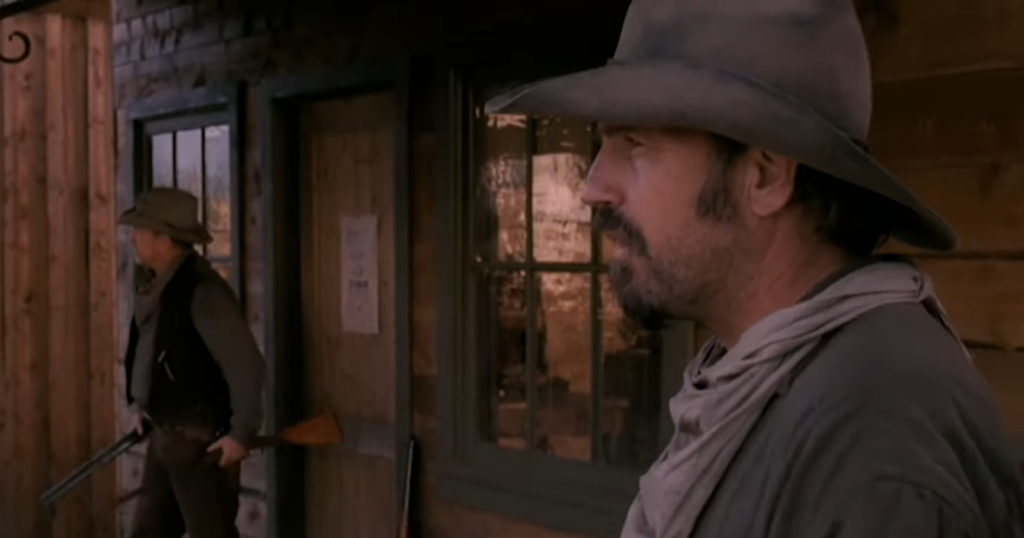 two men in cowboy hats near the buildings with windows