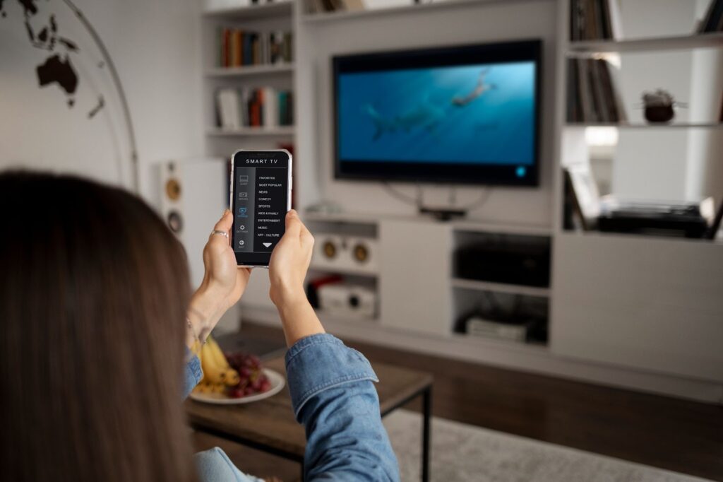 A woman adjusts the TV with her phone