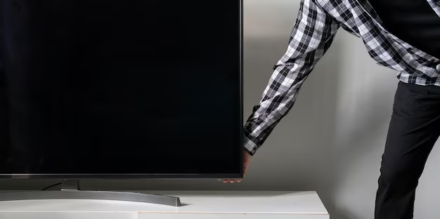A man touches the TV to check if it is warm